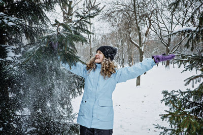 Hello winter, happy wintertime. happy young curly woman with hands raised up celebrating winter