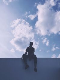 Low angle view of silhouette man sitting against sky