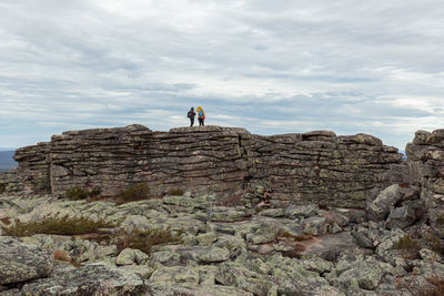 Low angle view of man standing on cliff against sky