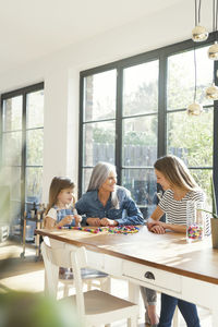 Grandmother and granddaughter and mother threading beads