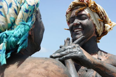 Low angle view of people in mud against blue sky