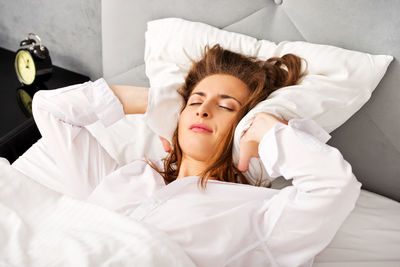 Women lying on bed hiding face by pillow