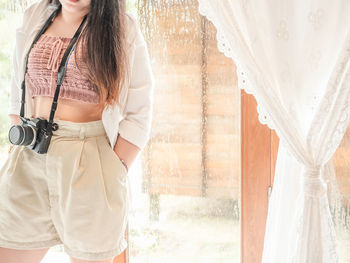 Midsection of woman standing by window