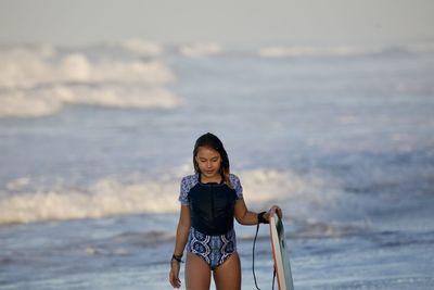 Girl holding surfboard on beach