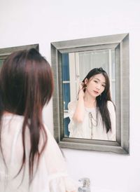 Portrait of smiling young woman in front of a mirror