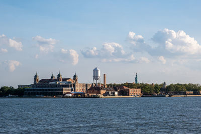 Buildings at waterfront against cloudy sky