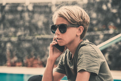 Portrait of young man wearing sunglasses sitting outdoors