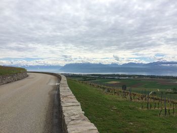 Road amidst agricultural field against sky