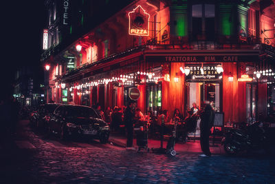 Group of people walking on illuminated street at night