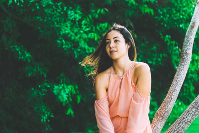 Young woman sitting on tree trunk