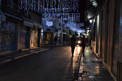 People walking on illuminated street at night