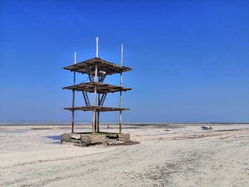 Lifeguard hut on beach against clear blue sky