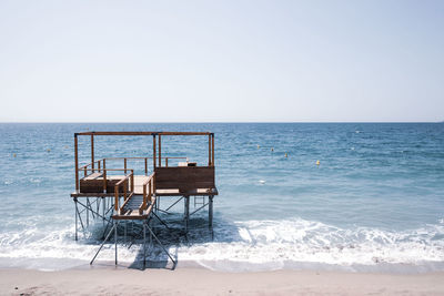 Chair on beach against clear sky