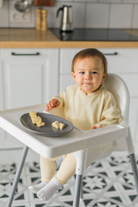 Portrait of cute baby boy sitting on table