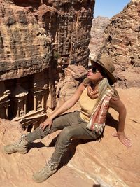 Young woman sitting on rock against mountain