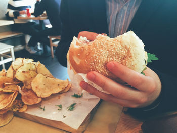 Midsection of man having burger at restaurant