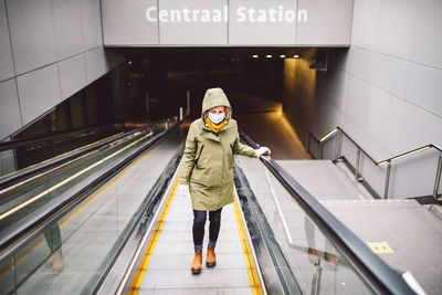 Rear view of woman standing on escalator