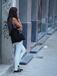 Rear view of woman standing on footpath