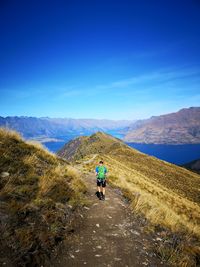 Rear view of man hiking on mountain against sky