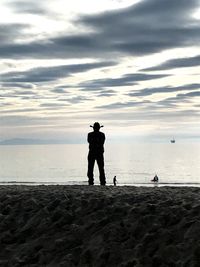 Silhouette men standing on beach against sky during sunset