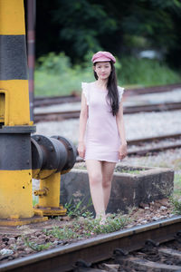 Portrait of a smiling young woman standing on railroad track