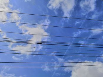 Low angle view of power lines against blue sky