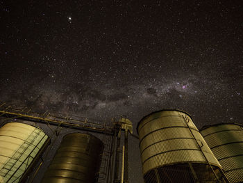 Low angle view of storage tanks against sky at night