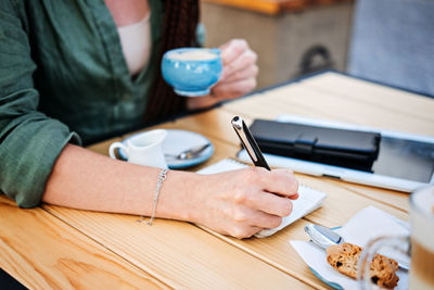 To do list, planning for freelancers. woman holding pens and papers making notes and drinking