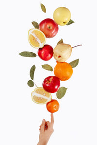 Close-up of hand holding fruits against white background