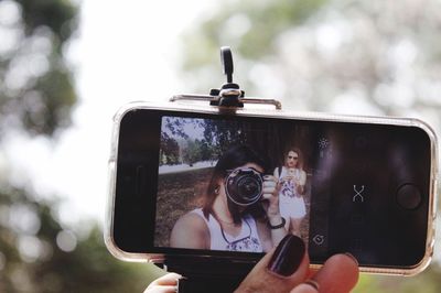 Photographer taking picture of woman holding mobile phone