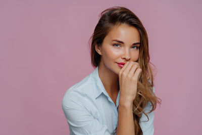 Close-up of beautiful woman against pink background