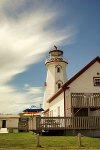Low angle view of lighthouse by building against sky