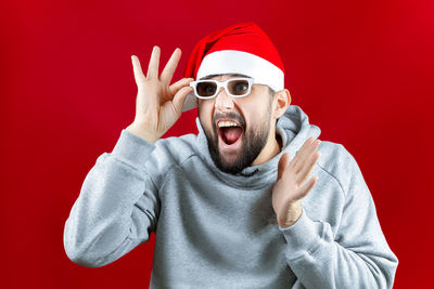 Portrait of man wearing sunglasses against red background