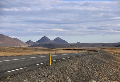 Empty road leading towards mountains against sky