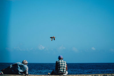 Men flying over sea against sky