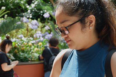 Close-up of young woman wearing eyeglasses against plants