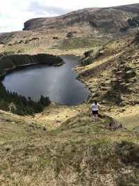 Rear view of man on lake by mountain