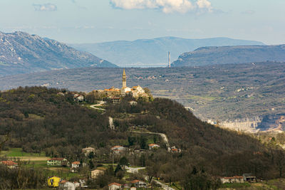 Scenic view of town by mountains against sky
