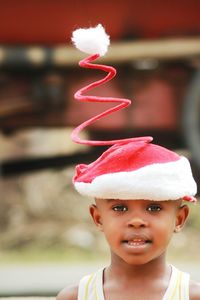 Close-up portrait of cute boy wearing spiral santa hat outdoors