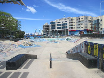 Road by buildings in city against sky