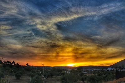 Scenic view of landscape against dramatic sky during sunset