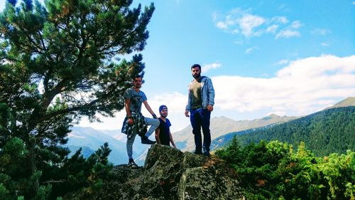 Friends standing on mountain peak against sky
