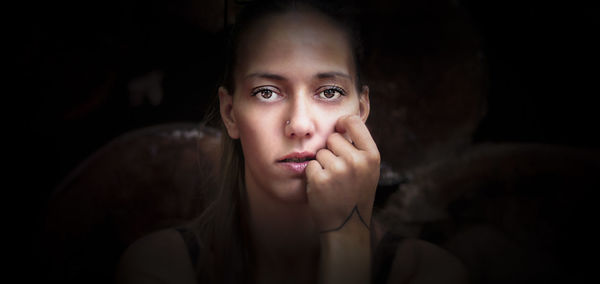 Close-up portrait of young woman against black background