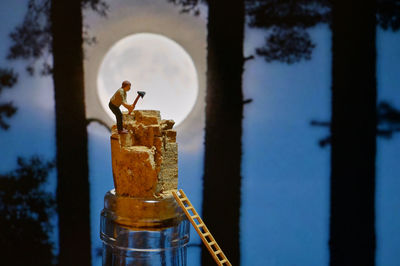 Miniature lumberjack worker cutting wine cork with a large ax in the forest