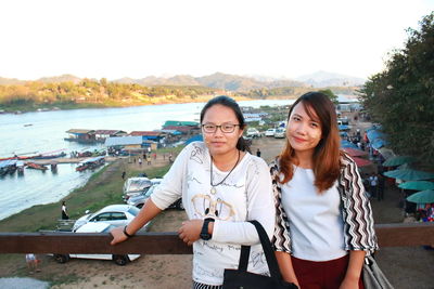 Portrait of friends standing against lake in town