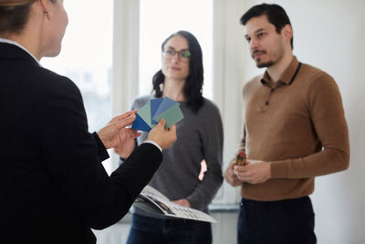 Female estate agent showing color samples to couple in new house