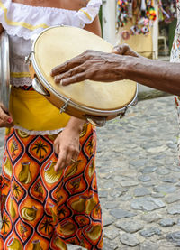 Tambourine player with a woman in typical clothes in the background in pelourinho, salvador, bahia
