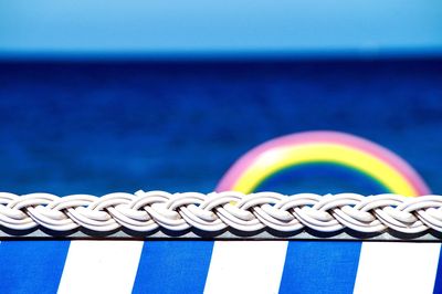 Close-up of metallic railing against sea against blue sky