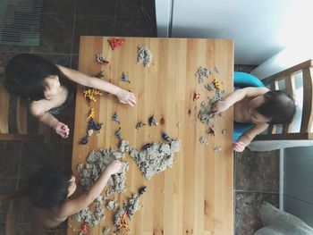 High angle view of shirtless siblings playing with toys at table