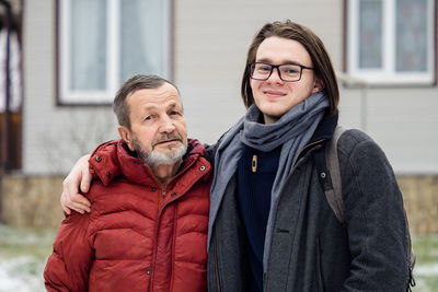 Portrait of senior man wearing warm clothing standing with grandson outdoors